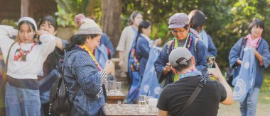 Tanımlanamayan Tayland 'lı kadın turistler, Tayland' ın Lamphun kentindeki Karen köyünde 12 Aralık 2019 tarihli iplik balosundan kolye yapmayı öğreniyor.