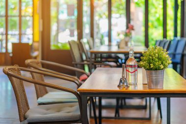 Garsonu aramak için küçük bir zil ve alüminyum bir tencerede suni çiçekler ve kahve dükkanındaki bir masaya yerleştirilmiş su şişesi..