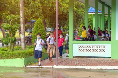 Kanchanaburi, Tayland-2 Temmuz 2020: Taylandlı öğrenciler okuldan sonra kendilerini Coronavirus 'tan (Covid-19) korumak ve KTR okulunda yağmur durduktan sonra evlerine dönmek için çeşitli tıbbi maskeler takıyorlar.