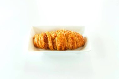 Beyaz tabakta sosisli kruvasan. Taze pişmiş kruvasan ekmeği ve sosis beyaz arka planda izole edilmiş. Hamurda sosis..