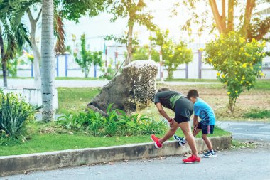 Sportif ve mutlu bir annenin oğlunu bahçede egzersiz yapmadan önce esneme hareketleri yaparken izlemesi. Atletik aile dışarıda birlikte egzersiz yapıyor. Çocuk bakımı spor aktivitesi konsepti