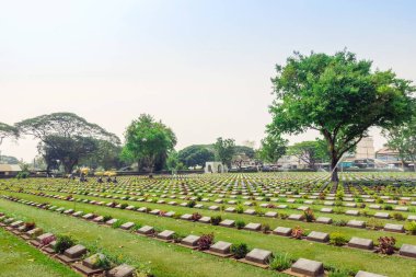 KANCHANABURI THAILAND - 21 Şubat: Kimliği belirsiz işçiler, 21 Şubat 2020 'de Kanchanaburi, Tayland' daki Kanchanaburi Müttefik Savaş Mezarlığı 'nda çiçek yenileyip dekore ediyorlar