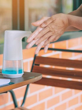 Coronavirus 'un (Covid-19) kafeteryaya girmeden önce masaya yayılmasını önlemek için otomatik alkol dağıtıcısı. Sağlık sigortası konsepti. Yeni normal yaşam tarzı. Seçici odak