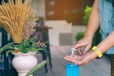 Coronavirus 'un (Covid-19) kafeteryaya girmeden önce yayılmasını önlemek için yaşlı kadının elleri mavi alkol jeli şişesine basıldı. Sağlık sigortası konsepti. Yeni normal yaşam tarzı. Seçici odak