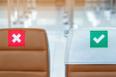 Corona virüsünü (Covid-19) önlemek için havaalanının bekleme terminalinde sosyal mesafeler için üzerinde etiket olan boş kahverengi sandalyeler. Güvenli yolculuklar. Yeni normal sosyal mesafeler..