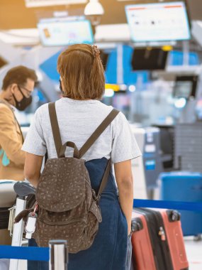 Corona virüsünü (Covid-19) önlemek için havaalanında personel maskesi takan yolcuların arka görüntüsü yüz maskesi takılır. Covid-19 salgınından sonra yeni normal seyahat kavramı.