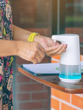 Coronavirus 'un (Covid-19) kafeteryaya girmeden önce masaya yayılmasını önlemek için otomatik alkol dağıtıcısı. Sağlık sigortası konsepti. Yeni normal yaşam tarzı. Seçici odak