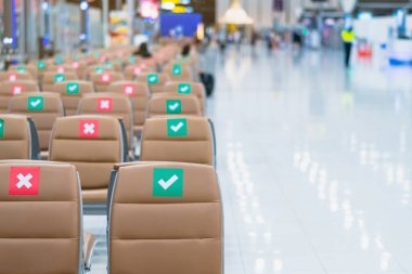 Corona virüsünü (Covid-19) önlemek için havaalanının bekleme terminalinde sosyal mesafeler için üzerinde etiket olan boş kahverengi sandalyeler. Güvenli yolculuklar. Yeni normal sosyal mesafeler..