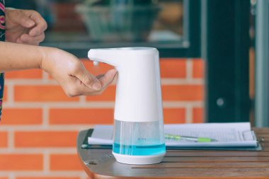 Coronavirus 'un (Covid-19) kafeteryaya girmeden önce masaya yayılmasını önlemek için otomatik alkol dağıtıcısı. Sağlık sigortası konsepti. Yeni normal yaşam tarzı. Seçici odak