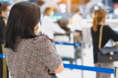 Corona virüsünü (Covid-19) önlemek için havaalanında personel maskesi takan yolcuların arka görüntüsü yüz maskesi takılır. Covid-19 salgınından sonra yeni normal seyahat kavramı.