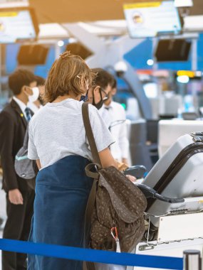 Corona virüsünü (Covid-19) önlemek için havaalanında personel maskesi takan yolcuların arka görüntüsü yüz maskesi takılır. Covid-19 salgınından sonra yeni normal seyahat kavramı.