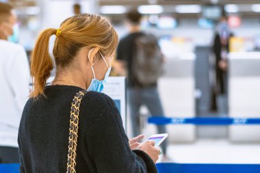 Corona virüsünü (Covid-19) önlemek için havaalanında personel maskesi takan yolcuların arka görüntüsü yüz maskesi takılır. Covid-19 salgınından sonra yeni normal seyahat kavramı.