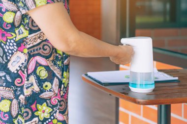 Coronavirus 'un (Covid-19) kafeteryaya girmeden önce masaya yayılmasını önlemek için otomatik alkol dağıtıcısı. Sağlık sigortası konsepti. Yeni normal yaşam tarzı. Seçici odak