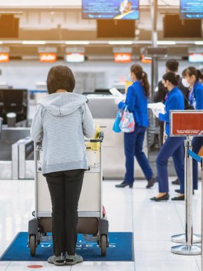 Corona virüsünü (Covid-19) önlemek için havaalanında personel maskesi takan yolcuların arka görüntüsü yüz maskesi takılır. Covid-19 salgınından sonra yeni normal seyahat kavramı.