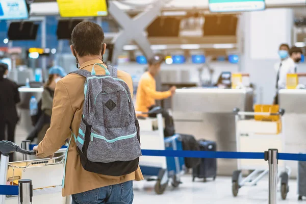 Corona virüsünü (Covid-19) önlemek için havaalanında personel maskesi takan yolcuların arka görüntüsü yüz maskesi takılır. Covid-19 salgınından sonra yeni normal seyahat kavramı.