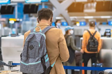 Corona virüsünü (Covid-19) önlemek için havaalanında personel maskesi takan yolcuların arka görüntüsü yüz maskesi takılır. Covid-19 salgınından sonra yeni normal seyahat kavramı.