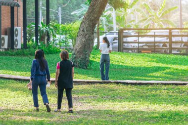 Asyalı kadınların yeşil bahçede yan yana yürüdüğünü gördüm. Parkta birlikte yürüyen iki kadın arkadaş. Mutlu arkadaşlar dışarıda yeşil doğada birlikte vakit geçiriyorlar. Doğanın tadını çıkarıyorum.