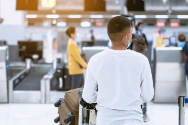 Corona virüsünü (Covid-19) önlemek için havaalanında personel maskesi takan yolcuların arka görüntüsü yüz maskesi takılır. Covid-19 salgınından sonra yeni normal seyahat kavramı.