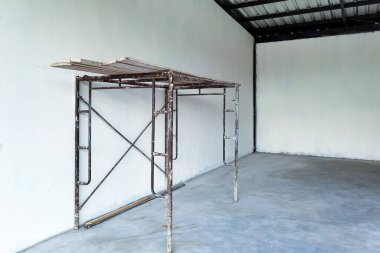 İç yapı inşaatı ve beton duvarların boyanması için yapı iskelesi sağlayın. İskeleli boş beyaz oda. Tadilat sırasında eski bir ev. İnşaat alanının içindeki eski yapı iskelesi..