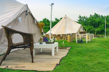 Yeşil çimenlikteki tatil çadırları ve dinlenme yerleri doğal parktaki ağaçların arasında. Yazın doğada kamp çadırı. Seyahat geçmişi. Açık havada piknik yapmak için. Dinlenme yeri ve çadırı olan kamp..