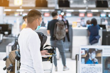 Corona virüsünü (Covid-19) önlemek için havaalanında personel maskesi takan yolcuların arka görüntüsü yüz maskesi takılır. Covid-19 salgınından sonra yeni normal seyahat kavramı.