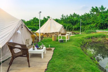 Yeşil çimenlikteki tatil çadırları ve dinlenme yerleri doğal parktaki ağaçların arasında. Yazın doğada kamp çadırı. Seyahat geçmişi. Açık havada piknik yapmak için. Dinlenme yeri ve çadırı olan kamp..