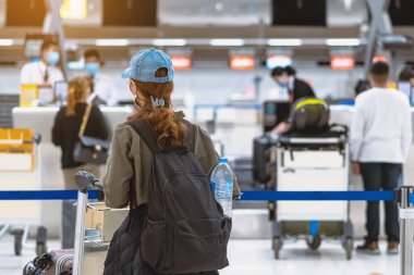 Corona virüsünü (Covid-19) önlemek için havaalanında personel maskesi takan yolcuların arka görüntüsü yüz maskesi takılır. Covid-19 salgınından sonra yeni normal seyahat kavramı.