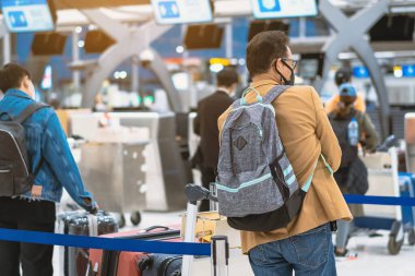 Corona virüsünü (Covid-19) önlemek için havaalanında personel maskesi takan yolcuların arka görüntüsü yüz maskesi takılır. Covid-19 salgınından sonra yeni normal seyahat kavramı.