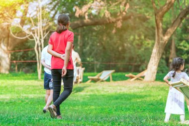 Asyalı bir kadının yeşil bahçede tek başına dolaşması. Ayakta duran kadın, ağaçların ve yeşil çimenlerin arasındaki çimlere sırtını döndü. Mutlu insanlar dışarıda yeşil doğada vakit geçirir..