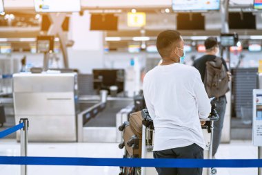 Corona virüsünü (Covid-19) önlemek için havaalanında personel maskesi takan yolcuların arka görüntüsü yüz maskesi takılır. Covid-19 salgınından sonra yeni normal seyahat kavramı.