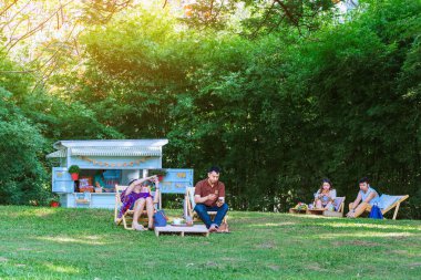 KANCHANABURI THAILAND - 4 Mayıs 2020: Tanımlanamayan Taylandlı çift 4 Mayıs 2020 tarihinde Kanchanaburi, Tayland 'da bulunan Mulberry Mellow' da dinlenmek ve akıllı telefon kullanmak için güverte sandalyelerinde oturuyorlar