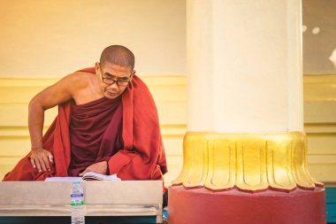 PAGAN-Myanmar, 21 Ocak 2019: Tanımlanamayan keşiş Shwezigon Pagoda 'da Budist yazıtlarıyla birlikte Pagan, Myanmar' da 21 Ocak 2019 'da meditasyon yapar ve dua eder..