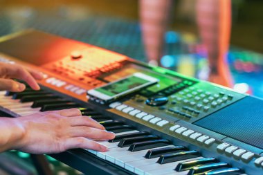 Erkek müzisyenin elleri konser sahnesinde dijital elektronik klavye sentezleyicilerine basıyor. Piyanist elleri elektronik piyanonun anahtarlarını çalar. Piyano çalan piyanist. Eldeki seçici odaklanma.