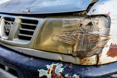 Arabanın farı kırılmış ve şeffaf bantla kapatılmış. Kırık araba farları bant ile tamir edildi. Hasarlı arabanın farları kazara kırılmış ve şeffaf koli bandıyla kaplanmış.