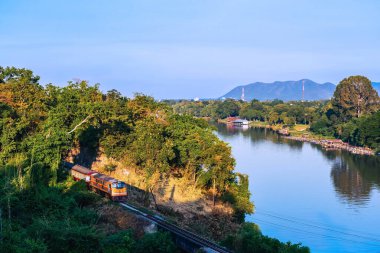 Kwai nehri boyunca tren yolculuğu. Trenin Tham Khao Pun Tapınağı 'ndaki yeşil tepelerle çevrili ünlü tren yolu kavşağının manzarası. 2. Dünya Savaşı Demiryolu, Tayland.