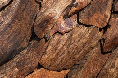 Yıpranmış ahşap döşeme dokusu. Yanmış kenarları olan istiflenmiş odun parçaları. Marangozluk ve marangozluk için düzensiz yaşlı kereste blokları yığını. Eski yanmış ahşap dizilimi.