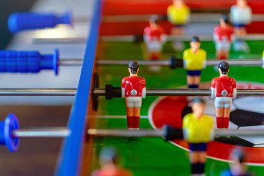 Kırmızı ve sarı oyuncuları olan renkli langırt masası. Güzel bir iç mekan eğlencesi ve masa futbolu yarışması geçmişi. Minyatür futbolculara özenle odaklanmış masa futbolu oyunu
