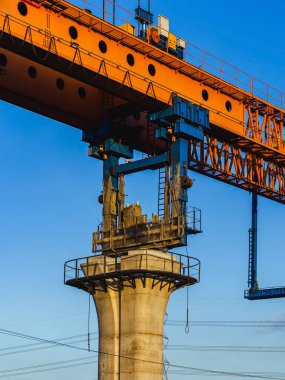 Kirişlerin montajı için gantry vinç kullanılarak büyük bir yükseltilmiş demiryolu viyadükünün yapımı. Ağır makinelere ve modernizasyon için beton direklere sahip yüksek demiryolu şantiyesi.