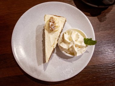 Kahve masasında bir dilim havuçlu kek ve krema.