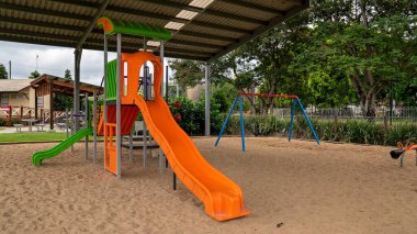 Mackay, Queensland, Avustralya - Ocak 2021: Kaygan kaydırak ve salıncaklı çocuklar için bir oyun alanı