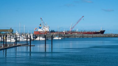Mackay, Queensland, Avustralya - Ocak 2021: Lüks tekneler arka planda bir konteynır gemisiyle marinaya demirlediler