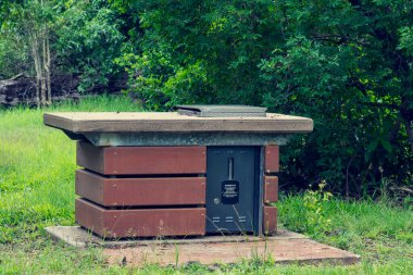 Beton yüzeyi ve çelik pişirme alanı olan bir açık hava barbeküsü.
