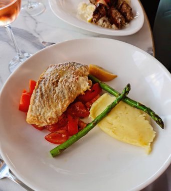 Domates yatağında kızarmış balık ve kuşkonmaz mızraklı patates püresi.