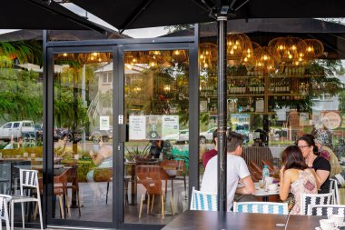 Brisbane, Queensland, Avustralya - Mart 2021: İnsanlar bir kafenin içinde ve dışında yemek yiyor