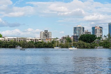 Brisbane, Queensland, Avustralya - Mart 2021: Nehirdeki yatlar ve motorlu tekneler yüksek binalara karşı