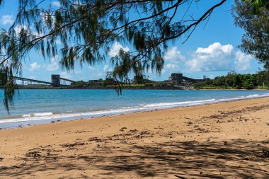 Kömür terminali termal ve metalürjik kömürü dünyanın dört bir yanındaki madenlerden limanlara ihraç ediyor, sahildeki ağaçların arasından görülüyor.