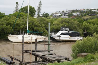 Yeppoon, Queensland, Avustralya - Nisan 2021: Düşük gelgitte demirlemiş tekneleri olan eski bir ahşap iskeleden düşme