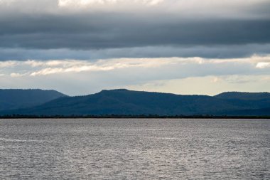 View across the water to the dam wall and beyond to the mountains and a stormy sky