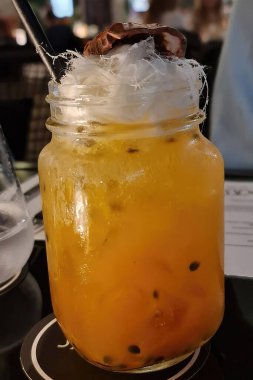 Close up of a passionfruit cocktail in a jar topped with fairy floss