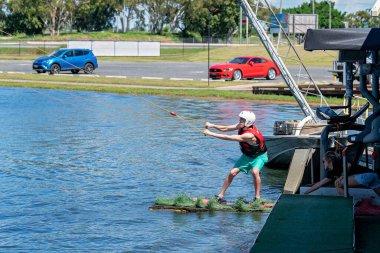 Mackay, Queensland, Avustralya - Nisan 2021: Kablo kayak parkında wakeboard öğrenen adam